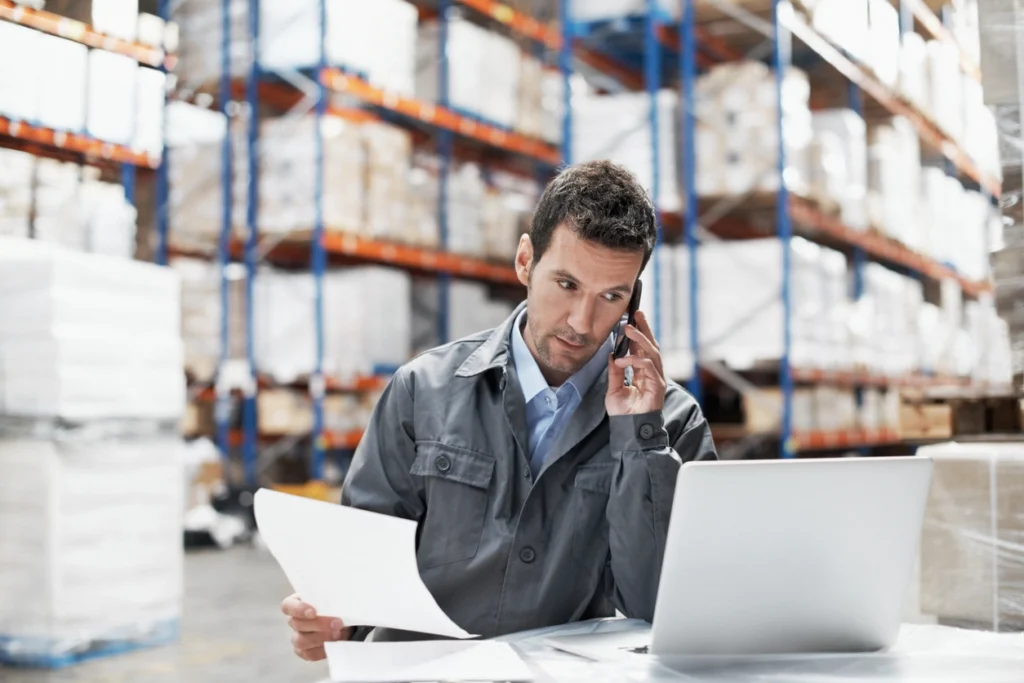 man in a warehouse talking through a phone to discuss order management challenges