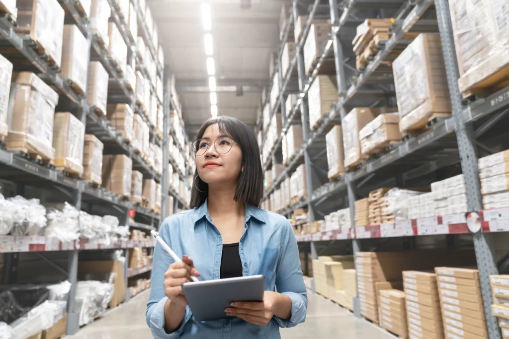 woman holding a styles and a tablet performing an audit in a warehouse